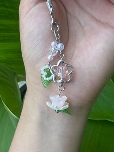 a person is holding onto a bracelet with flowers and pearls on it's side