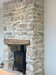 a stone fireplace with a wood burning stove in the center and white walls behind it