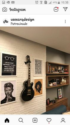 a guitar hanging on the wall next to some bookshelves with pictures on them