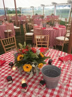 the table is set up with red and white checkered cloths, sunflowers and candles