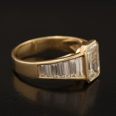 a yellow gold ring with three baguettes on the side and two diamonds in the middle