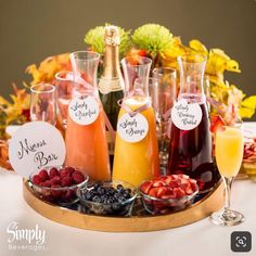 a tray filled with drinks and fruit on top of a table next to wine glasses