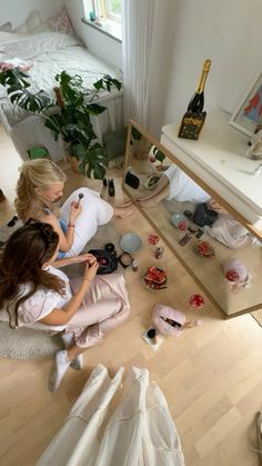 two women sitting on the floor in front of a mirror