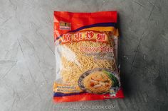 a bag of chow mein noodles sitting on top of a cement floor next to a knife