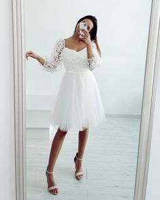 a woman taking a selfie in front of a mirror wearing a white wedding dress