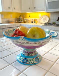 a bowl filled with fruit sitting on top of a kitchen counter