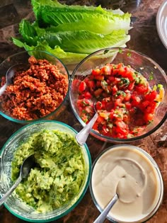 several bowls filled with different types of food on top of a marble table next to lettuce