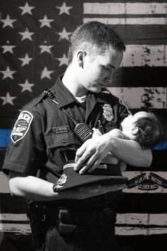 a police officer holding a baby in front of an american flag