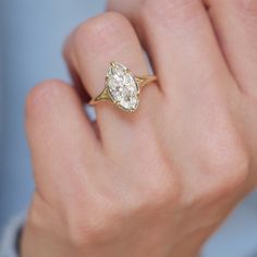 a close up of a person's hand holding a ring with a diamond on it