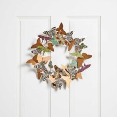 a wreath made out of paper butterflies hangs on the front door's white paneled door