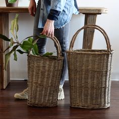 a woman standing next to two wicker baskets with plants in them on the floor