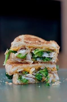 a grilled sandwich with broccoli and cheese on it is cut in half