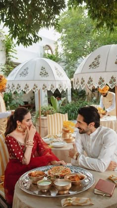 a man and woman sitting at a table with food