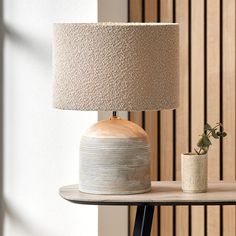 a table with a lamp on it and a potted plant sitting next to it