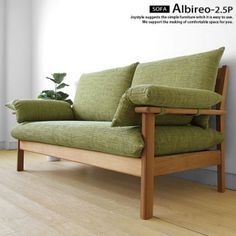 a green couch sitting on top of a hard wood floor next to a white wall