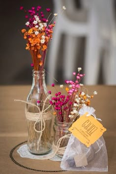 two vases with flowers in them sitting on a table next to a tag that says hello