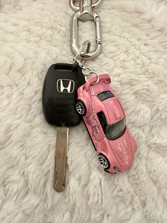 a pink car keychain with a black one and a red one on it