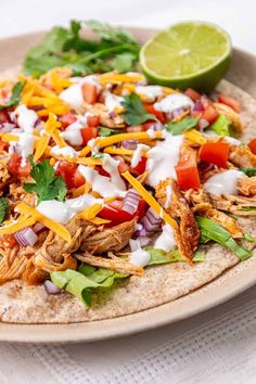 a tortilla topped with shredded chicken, tomatoes, onions, cheese and cilantro