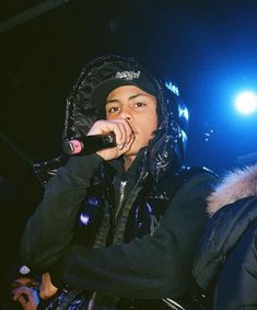 a man in black jacket holding a microphone up to his mouth while standing on stage