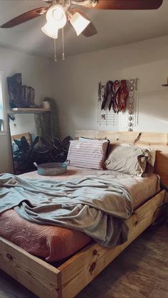 a bed sitting in a bedroom next to a window with a fan on top of it