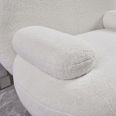 a white chair with a pillow on it's back and arm rest in the corner