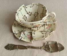 an antique tea cup and saucer with barbed wire on it, next to a spoon