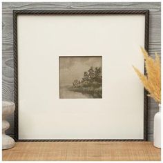 an old photo frame sitting on top of a table next to a vase with flowers in it