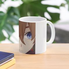 a coffee mug with an anime character's face and blue eyes sitting on a table