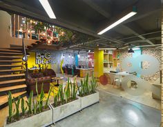 an office with plants in planters on the floor and stairs to the second floor