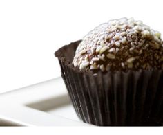 a chocolate cupcake with sprinkles sits on a white plate