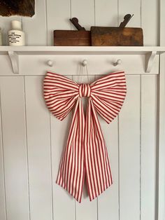 a red and white bow hanging on the wall next to a shelf with other items