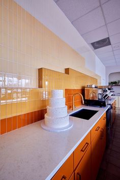 a three tiered cake sitting on top of a kitchen counter next to a sink