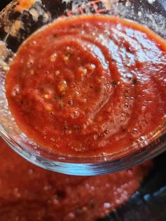 a glass bowl filled with marinara sauce on top of a stovetop burner