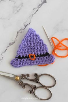 a purple crocheted hat sitting on top of a table next to scissors