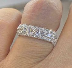 a woman's hand with a wedding ring on it and two diamonds in the middle