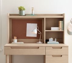 a desk with a lamp, books and other items on it next to a wall