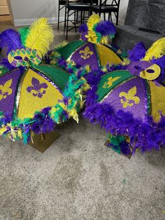 three mardi gras hats with purple, green and yellow feathers on the floor