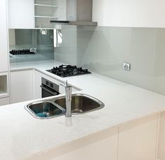 a kitchen with a sink, stove and counter top in the middle of it's white cabinetry