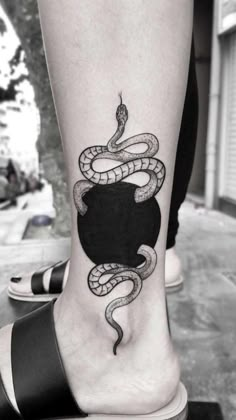 a black and white photo of a person's foot with a snake on it