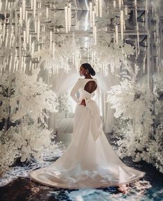 a woman in a white wedding dress standing in front of a backdrop with chandeliers