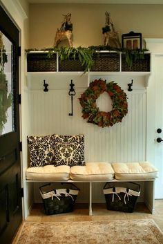 the entryway is decorated for christmas with wreaths on the wall and two benches