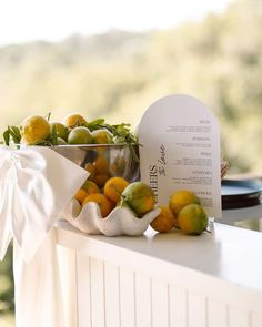 there is a metal bowl filled with oranges on the ledge next to a sign