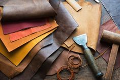 many different types of leathers are laid out on the table with scissors and other tools