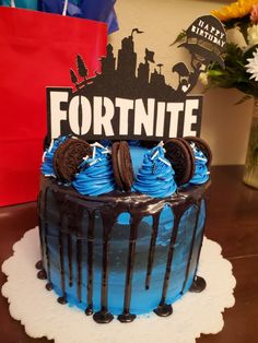 a blue cake with oreo cookies on top and the word fortnite written in black