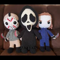 three crocheted dolls are standing next to each other on a brown couch,