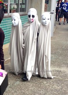 three people in white masks standing next to each other on the side of a street