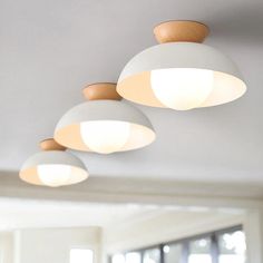 three circular lights hanging from the ceiling in a room with white walls and wood trim