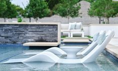 an outdoor swimming pool with lounge chairs and trees in the backgroung area