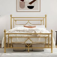 a white bed with gold frame and foot board in a bedroom next to a painting on the wall