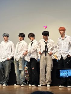 a group of young men standing next to each other on top of a wooden floor